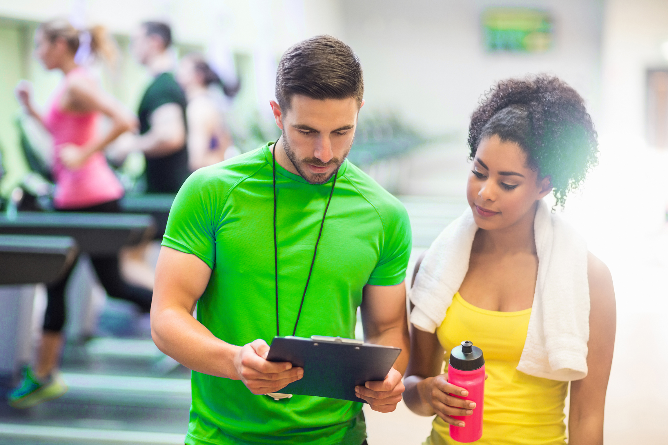 Fit woman talking to her trainer at the gym Fit woman talking to her trainer at the gym